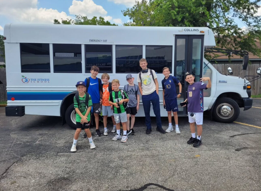 Group of kids smiling in front of school bus