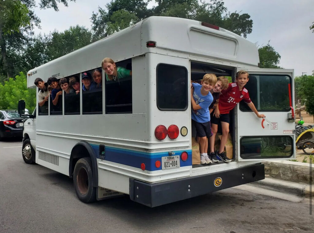Kids smiling from back of a school bus.
